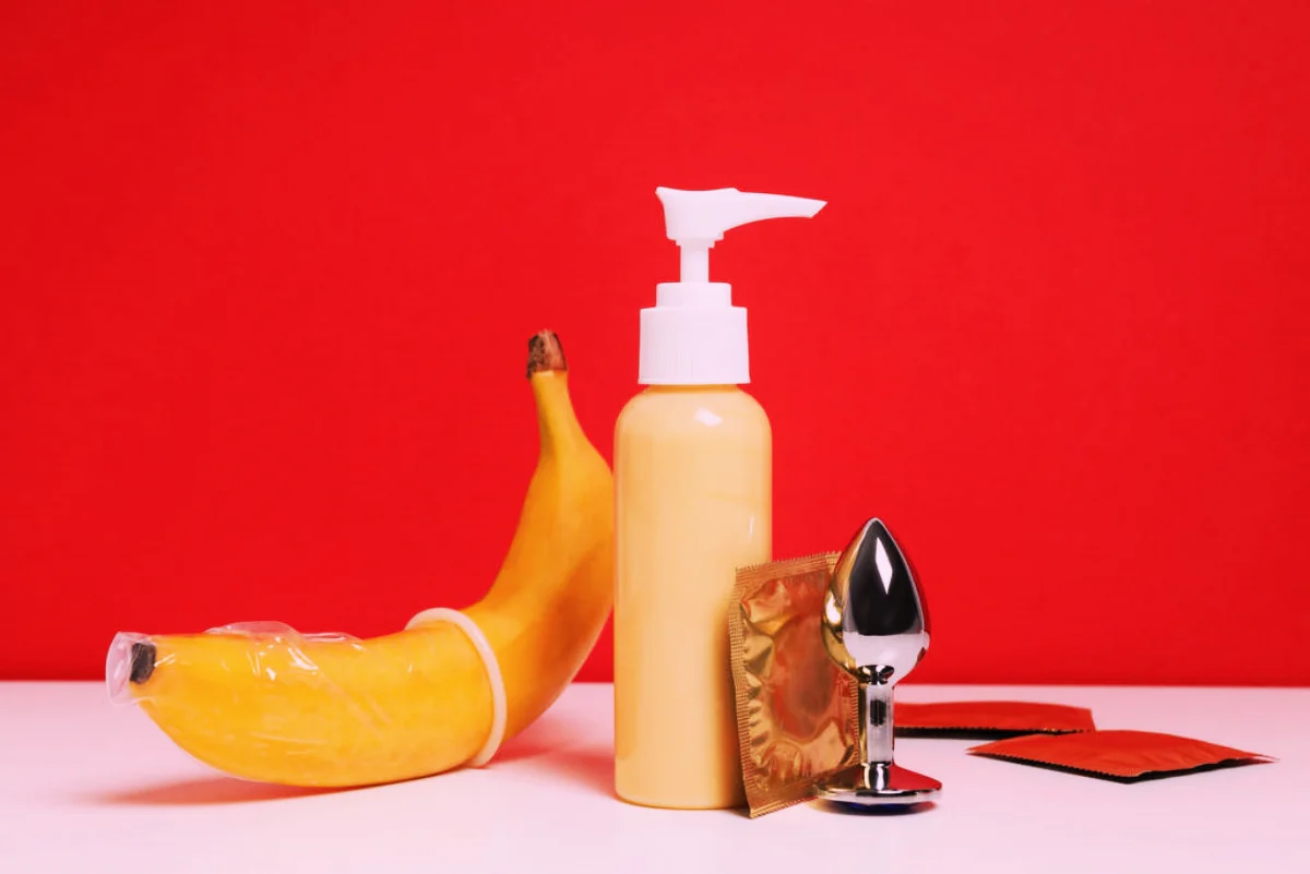 Lubricant, banana and condoms on a red background.